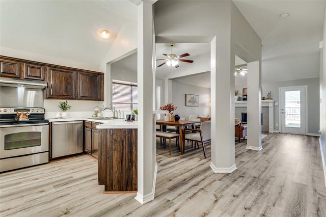 Welcoming eat-in kitchen featuring sleek stainless steel appliances, a contemporary hood vent, and a chic backsplash, perfect for casual dining and cooking in style.
