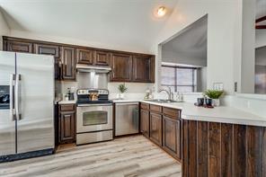 inviting eat-in kitchen, complete with sleek stainless steel appliances, a modern hood vent, and a stylish backsplash guard. 