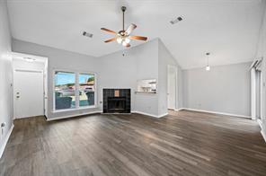 Living Room/ Dining Area featuring a textured ceiling, lofted ceiling, wood-style floors, fresh paint and ceiling fan