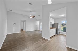 Unfurnished living room with vaulted ceiling, a tiled fireplace, ceiling fan, and dark wood-type flooring