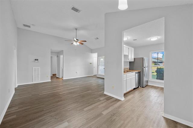 Unfurnished living room with vaulted ceiling, a tiled fireplace, ceiling fan, and dark wood-type flooring