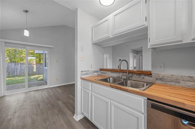Dining/Kitchen Nook room with dark wood-type flooring, pendant light, door and high vaulted ceiling