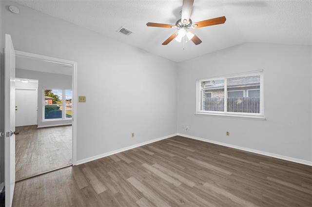 Primary bedroom with wood-type flooring, a closet, a textured ceiling, vaulted ceiling, and ceiling fan