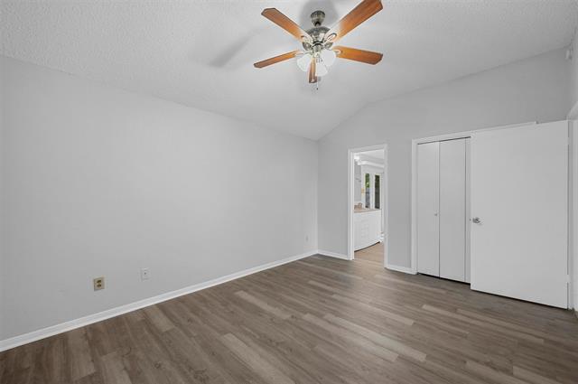 Primary bedroom featuring a textured ceiling, lofted ceiling, dark hardwood / wood-style flooring, and ceiling fan