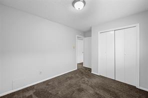 3rd bedroom featuring updated windows, a textured ceiling, a closet, and dark colored carpet