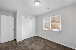 3rd bedroom featuring a textured ceiling and dark colored carpet