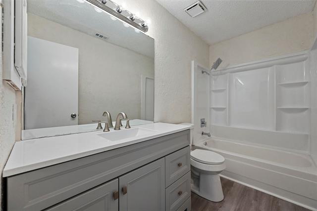 2nd bedroom featuring dark carpet, a textured ceiling and updated window