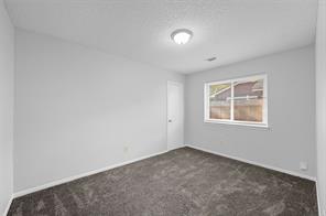 2nd bedroom with carpet featuring a textured ceiling and updated window