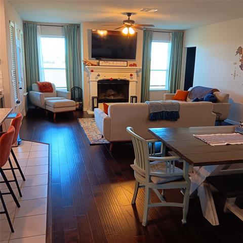 Living room and dining areas featuring ceiling fan and dark hardwood flooring