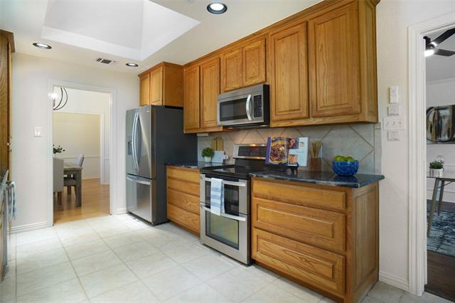 Kitchen featuring a raised ceiling, sink, backsplash, appliances with stainless steel finishes, and dark stone counters